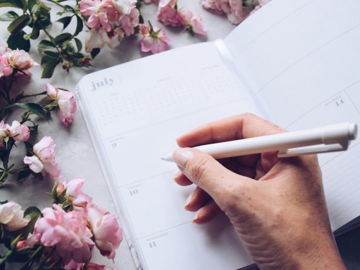 Woman is holding a pen to write in a daily planner