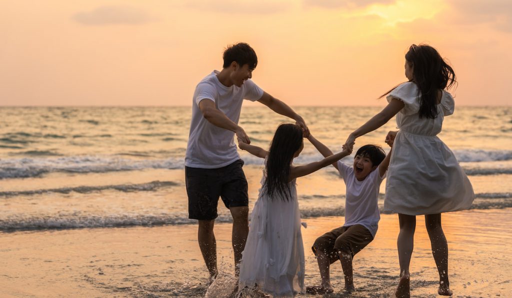 Asian young happy family enjoy vacation on beach in the evening.