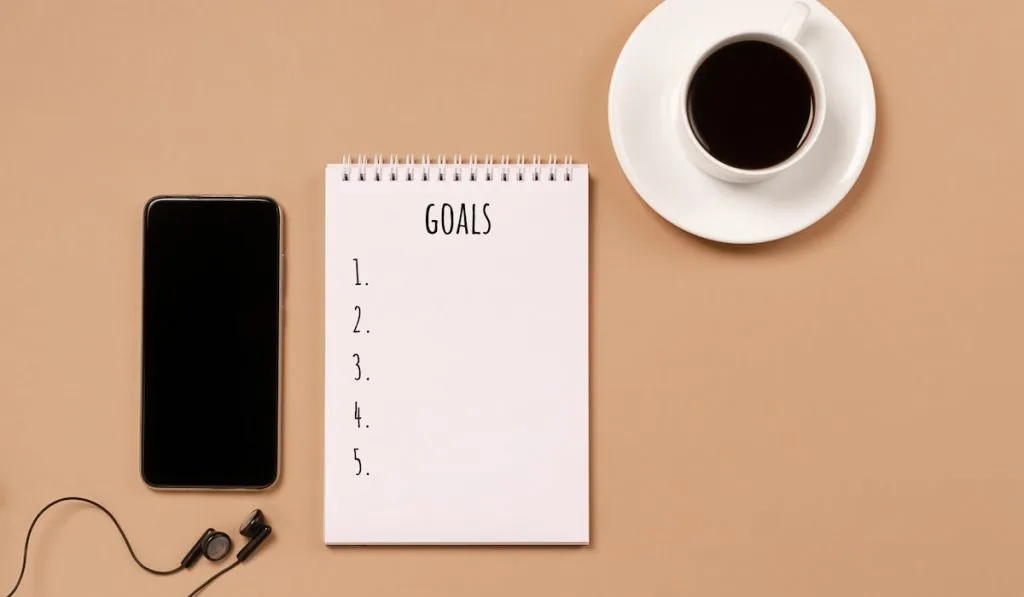 Blank notepad for action plans goals coffee cup phone pastel background