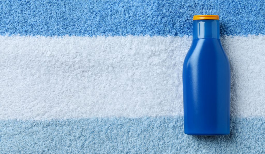 Blue bottle of sunscreen on towel background