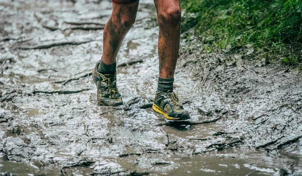 crop photo lower part of an athlete running on mud