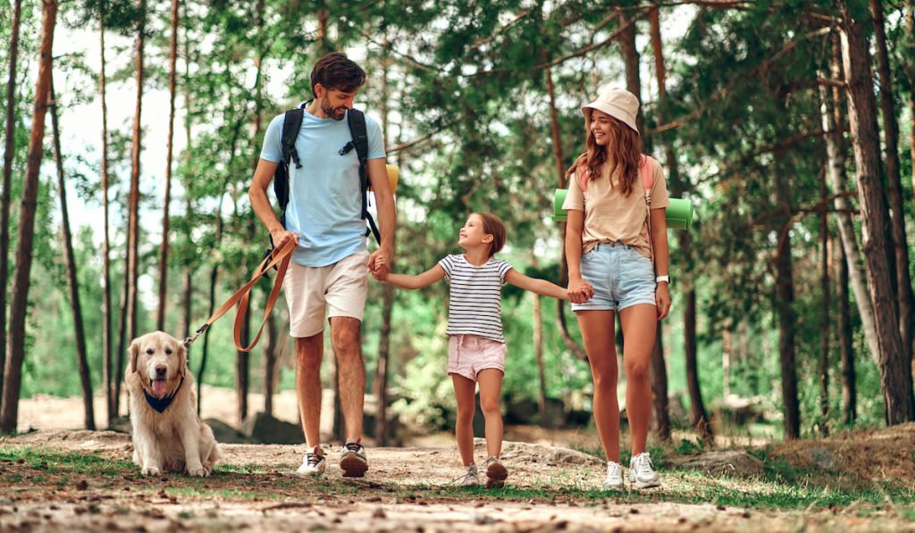 family of three with a dog on a camping vacation  