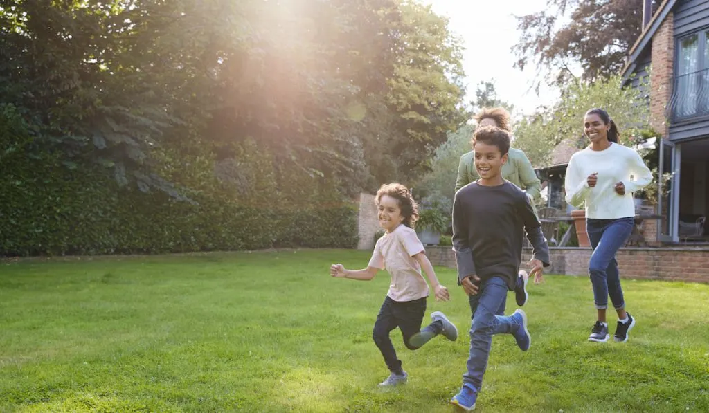 Family running on lawn outside house