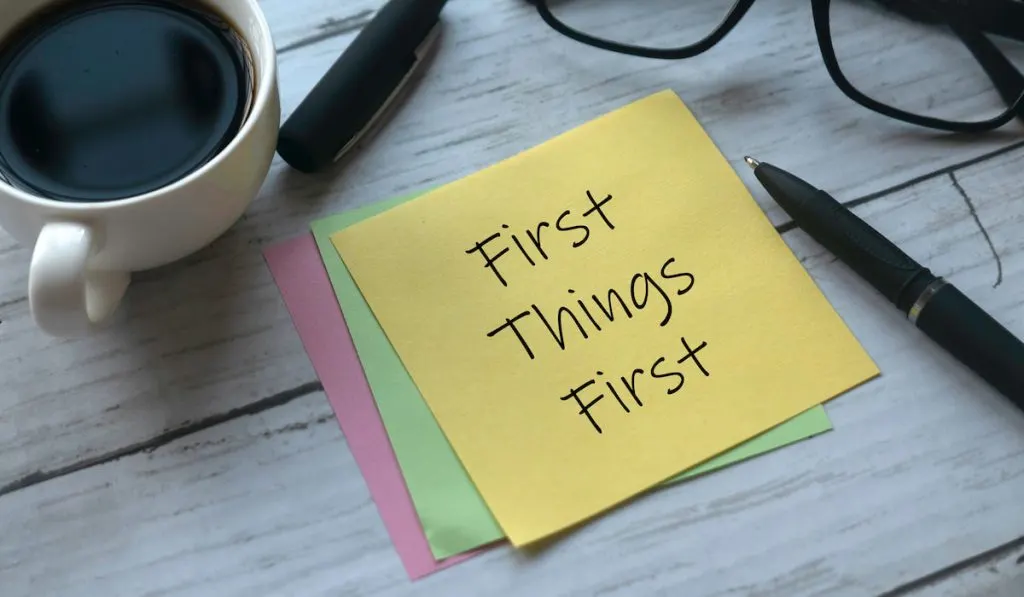 First things first quotation on a yellow sticky note