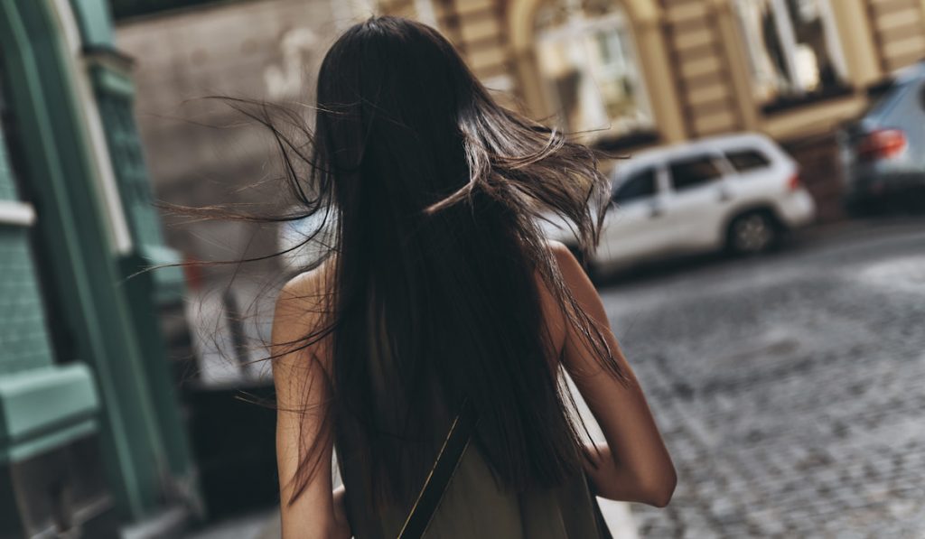 Follow your dream... Rear view of young woman walking down the street while spending time outdoors