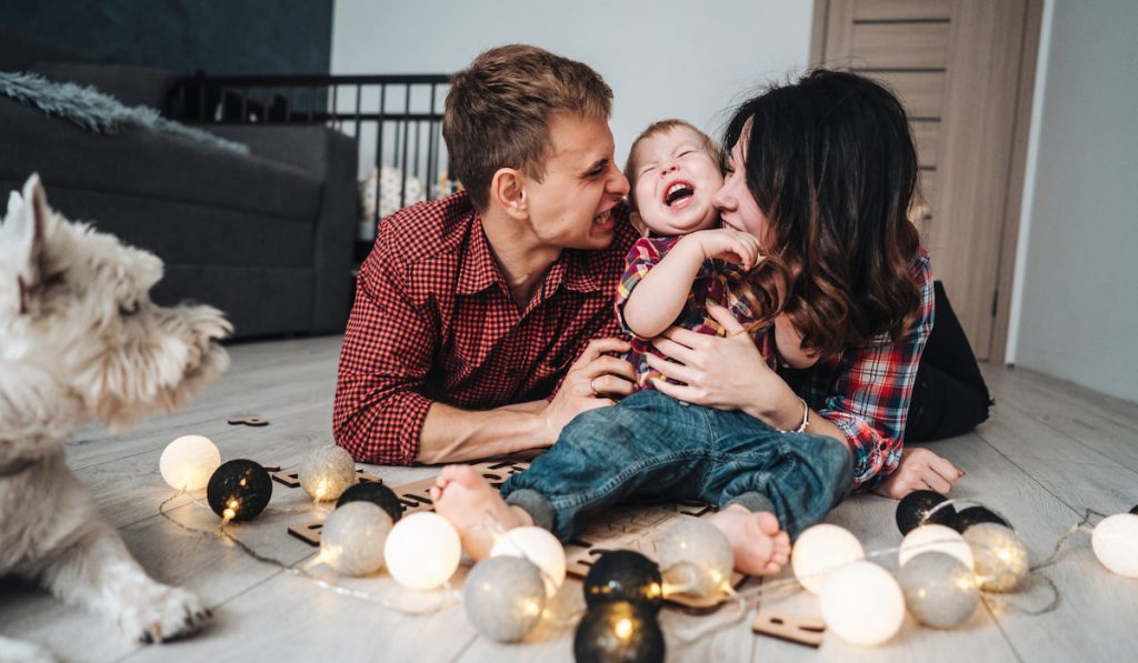 Happy family are playing together on the floor and their dog