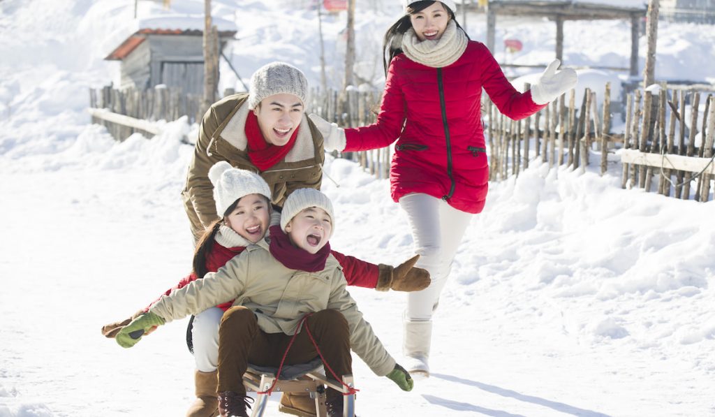 Happy family playing with sled in the snow