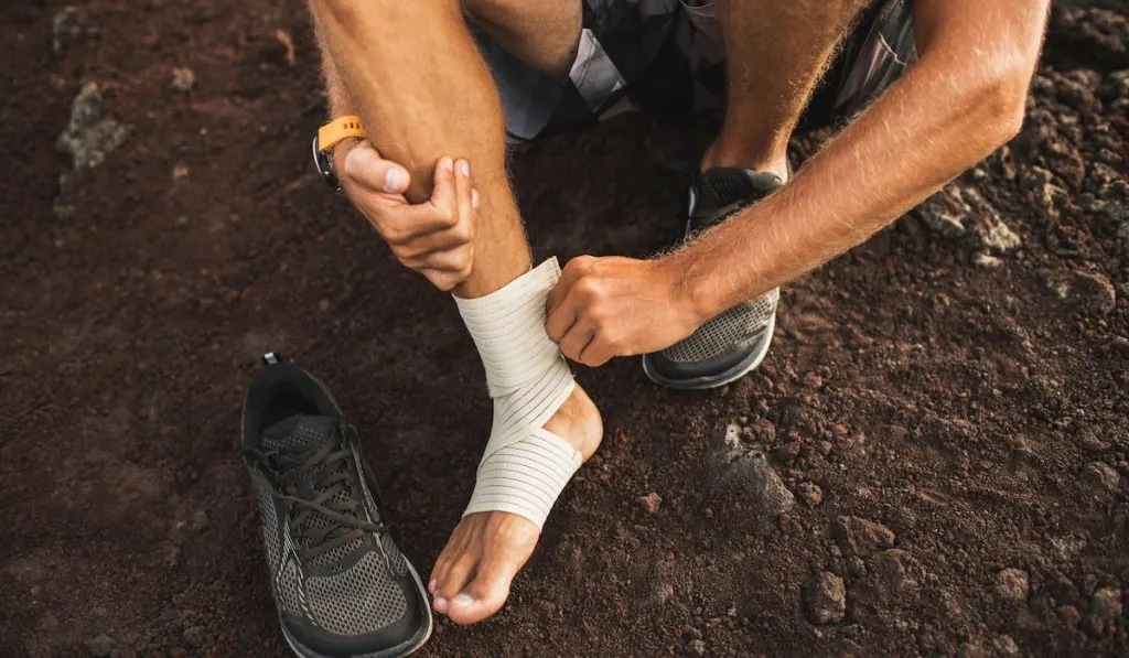Man bandaging injured ankle First aid for sprained ligament