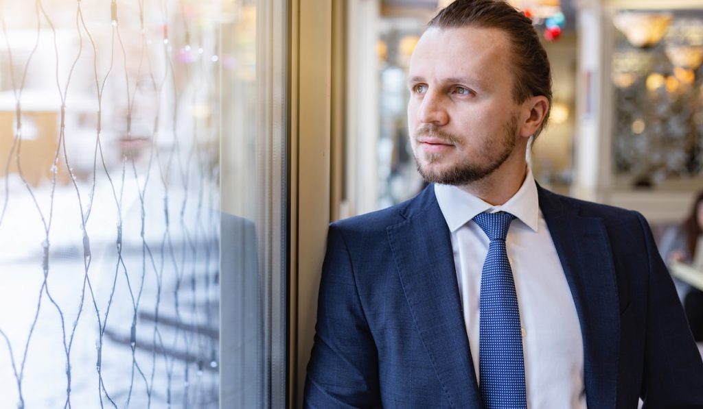 Man standing and looking dreamly in the window indoor