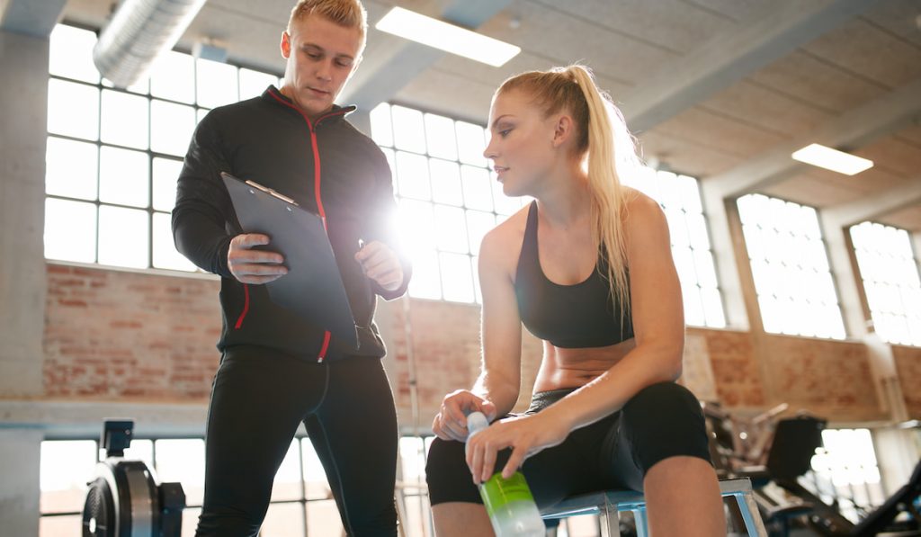 Personal trainer making an exercise plan for young woman