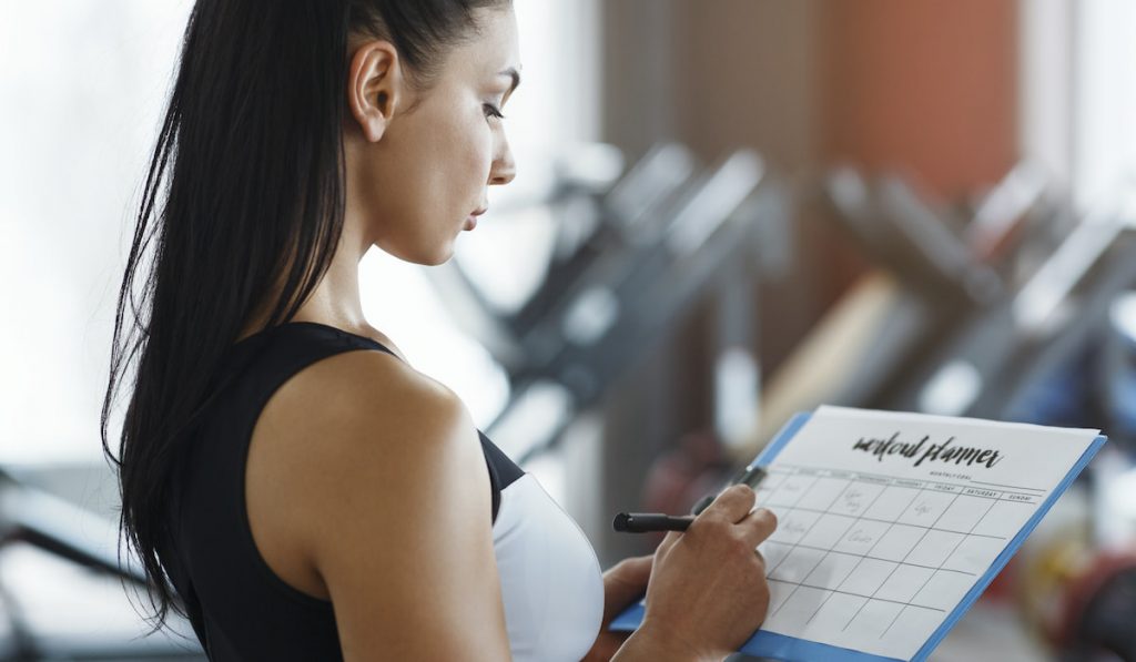 Personal trainer with clipboard making workout plan in gym
