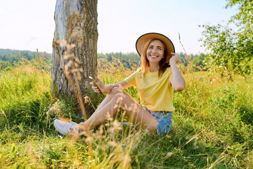 Portrait of content young woman sitting on meadow 