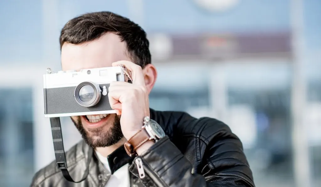 Smiling Man with photo camera outdoors