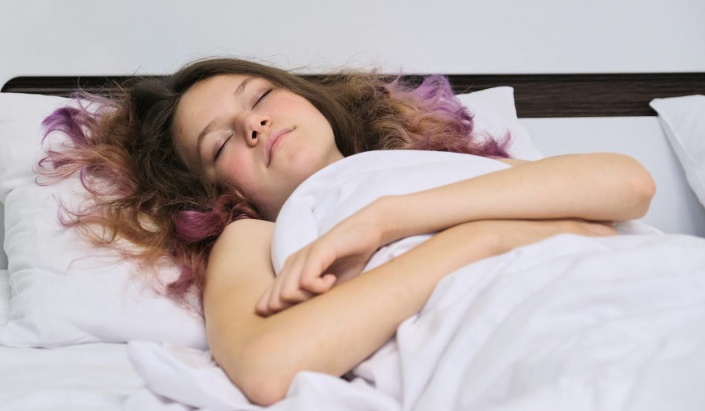 Teen girl sleeping at home in bed 