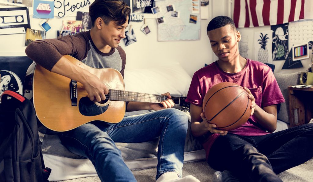 Teenage boys hanging out in a bedroom music and sports hobby concept 