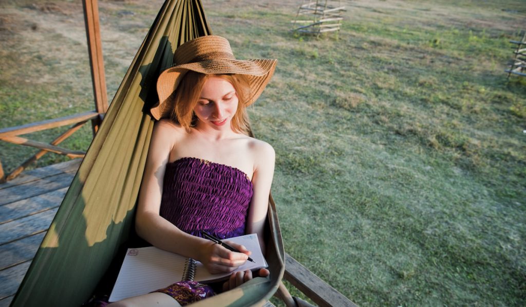 Tourist Writing her affirmation in her Diary in a Hammock