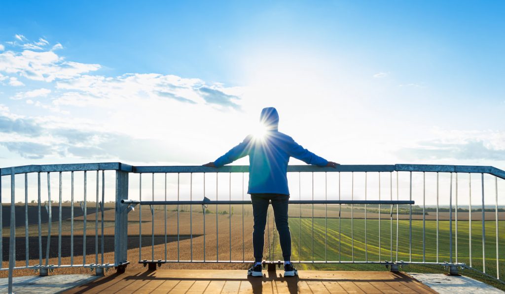 View from behind of a man standing at view point looking to beautiful landscape