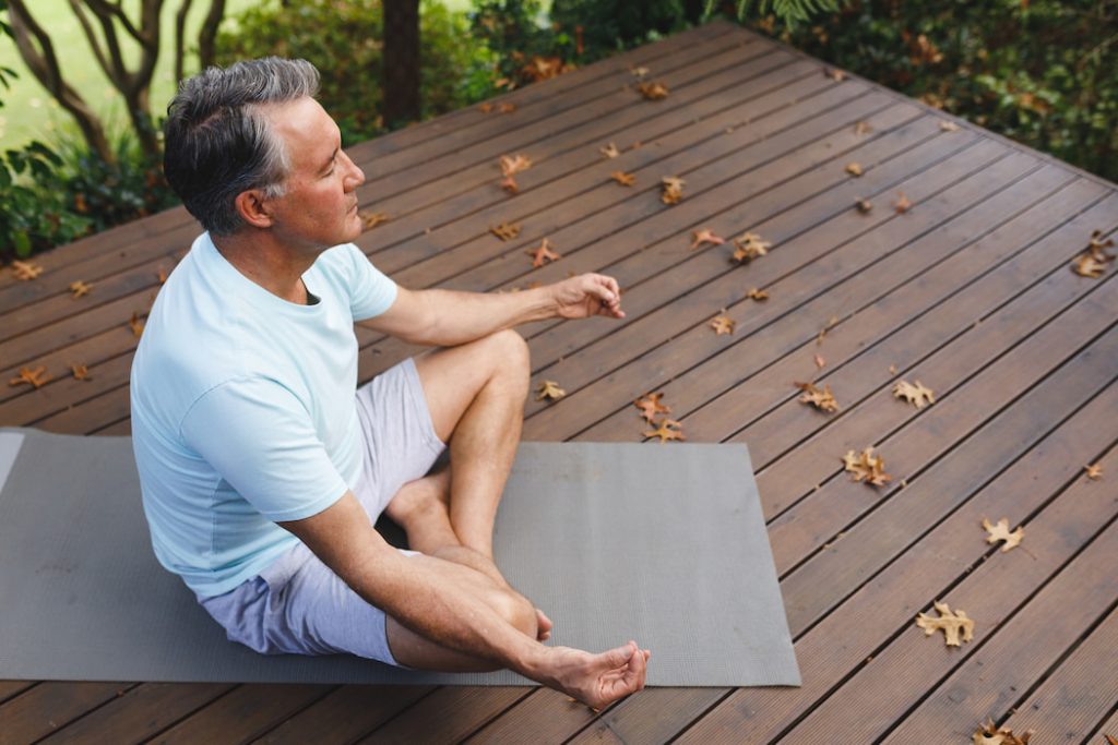 a man meditating on a wooden deck