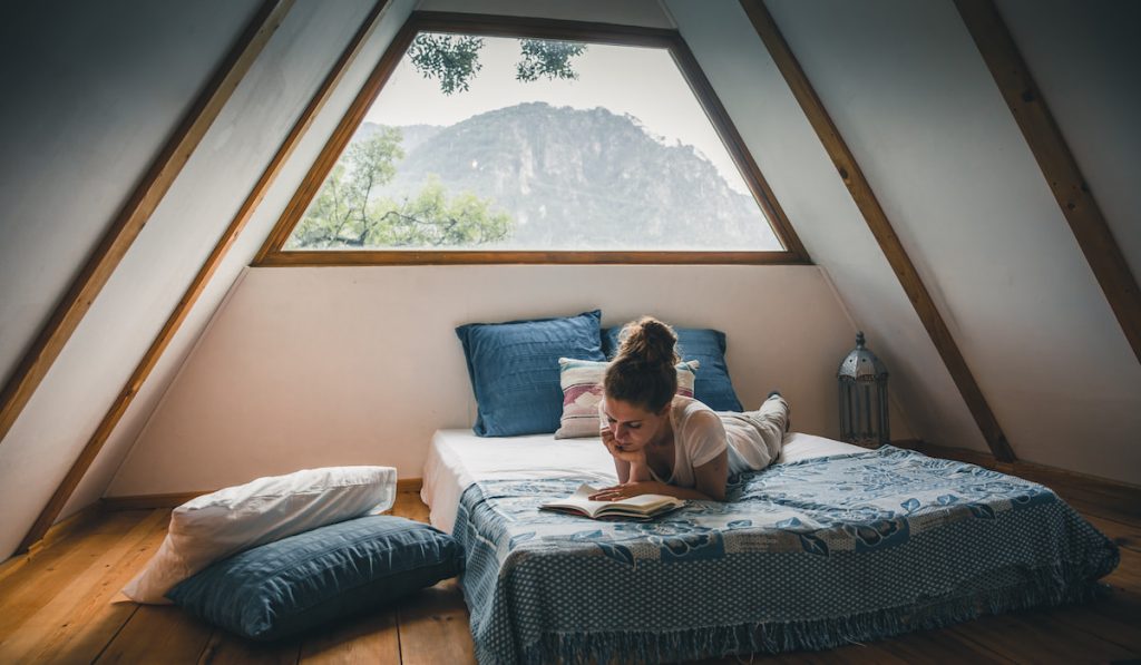 a woman reading a book while lying in bed in a room