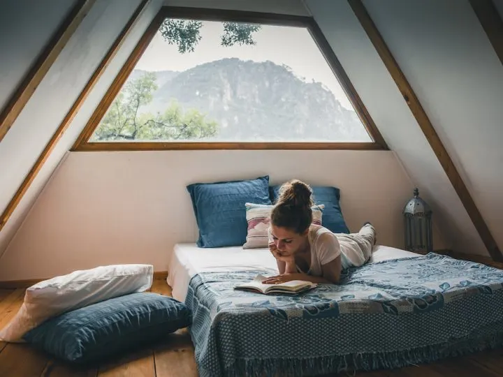 a-woman-reading-a-book-while-lying-in-bed-in-a-room