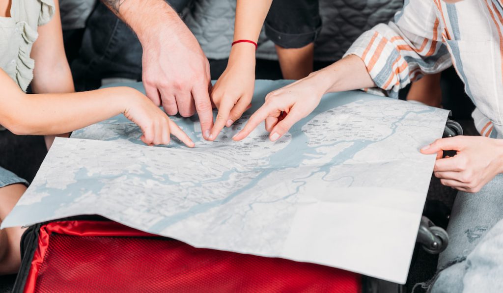 cropped shot of family pointing at map while planning trip