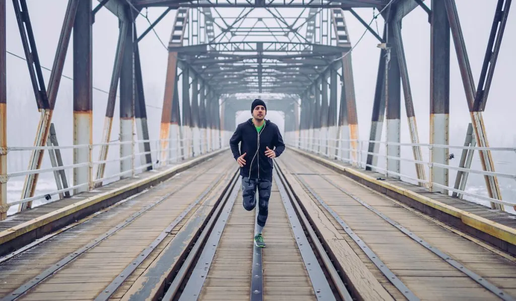 man running in the middle of the bridge