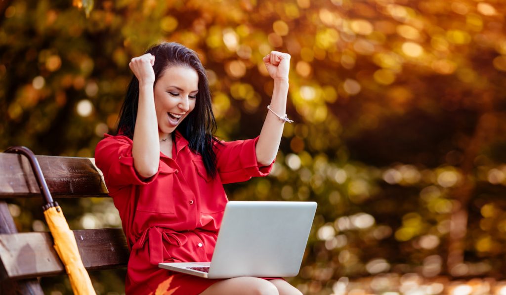 woman celebrating with a laptop on her lap