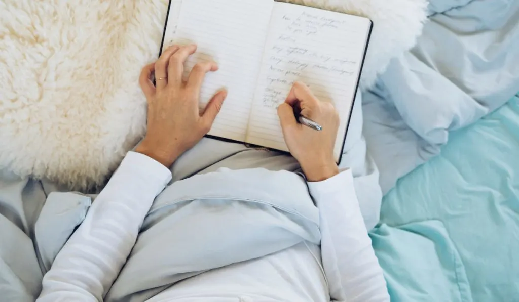 woman writing in her journal in bed